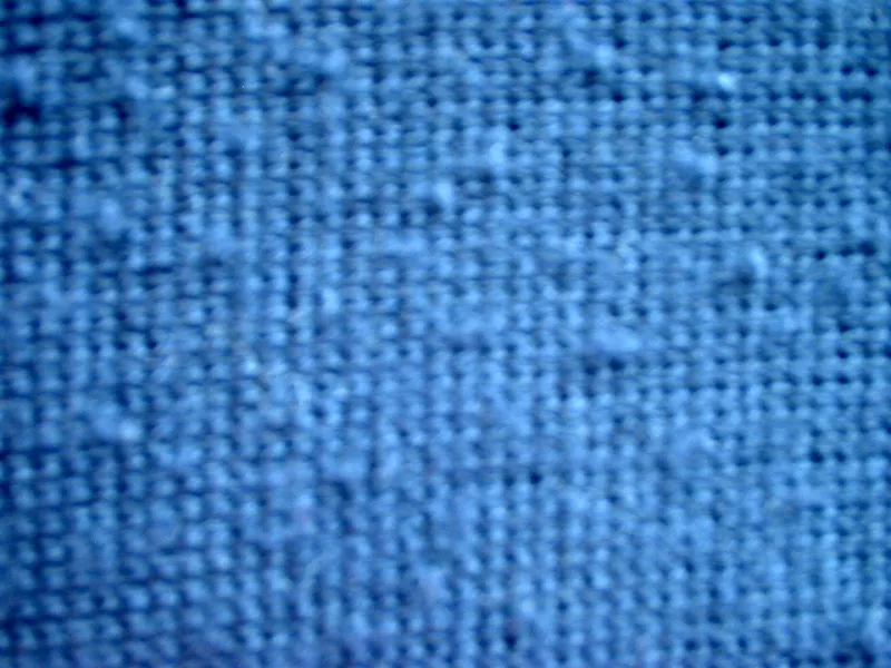 Detail modré pleteniny s drobnými žmolky.